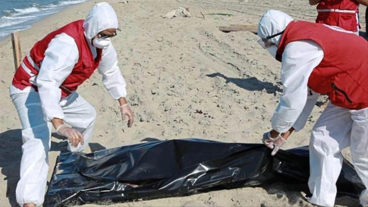 Libysche Mitarbeiter des Roten Halbmonds bergen die Leiche eines ertrunkenen Migranten. 
