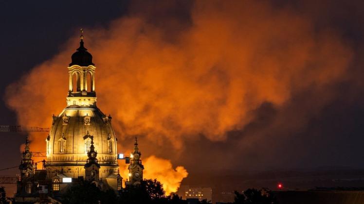 Dresdens Frauenkirche ist umgeben von feuerroten Rauchschwaden. Foto: dpa/Robert Michael