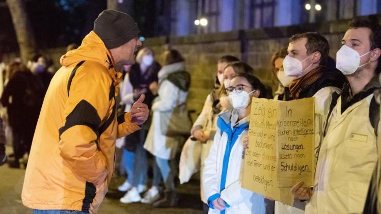 Ein Teilnehmer einer als „Spaziergang“ deklarierten Demonstration von Impfgegnern und Kritikern der Corona-Maßnahmen steht am Universitätsklinikum Dresden vor zahlreichen Gegendemonstranten.