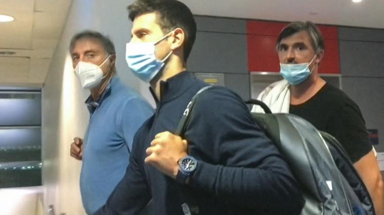 STR This screen grab from AFPTV shows Serbia's Novak Djokovic (C) walking ahead of his coach Goran Ivanisevic (R) after they disembarked from their plane at the airport in Dubai on January 17, 2022, after losing a legal battle on January 16 in Australia to stay and play in the Australian Open tennis tournament over his coronavirus vaccination status. (Photo by AFPTV / AFP)