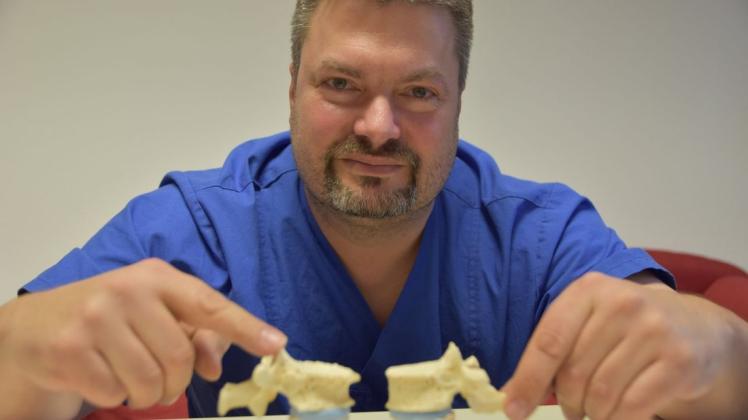 Norbert Bursch, Leitender  Oberarzt und Experte für  Schmerztherapie, zeigt beispielhaft am Wirbelmodell, wo Schmerzen entstehen können. Foto: Marco Julius