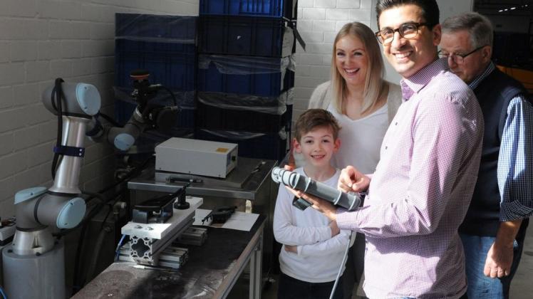 Mit einem selbstgebauten Roboter erleichtert Kassem Taleb (vorn), das Nacharbeiten industriell gefertigter Teile. Sohn Maximilian, Ehefrau Stefanie und Berater Jürgen Brinker (von links) sind fasziniert. Foto: Martin Schmitz