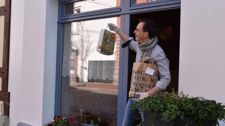 Buchhandel in Zeiten von Corona. Der Parchimer Buchhändler Tilo Tambach reicht Tüten mit Literatur an seine Kunden heraus.