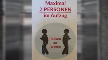 Der Hinweis vor dem Aufzug ist unübersehbar - aber ob Rücken an Rücken hilft, wenn eine der beiden Personen  ein „Hatschi“ nicht verhindern kann?