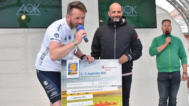 Der Sprecher der Ostseesparkasse Rostock, Ronny Susa (Mitte), überreichte den Spendenscheck über 15.000 Euro an Rostocks OB und Tour-Organisator Claus Ruhe Madsen (parteilos, l.). Der Sprecher der Ostseesparkasse Rostock, Ronny Susa (Mitte), überreichte den Spendenscheck über 15.000 Euro an Rostocks OB und Tour-Organisator Claus Ruhe Madsen (parteilos, l.).