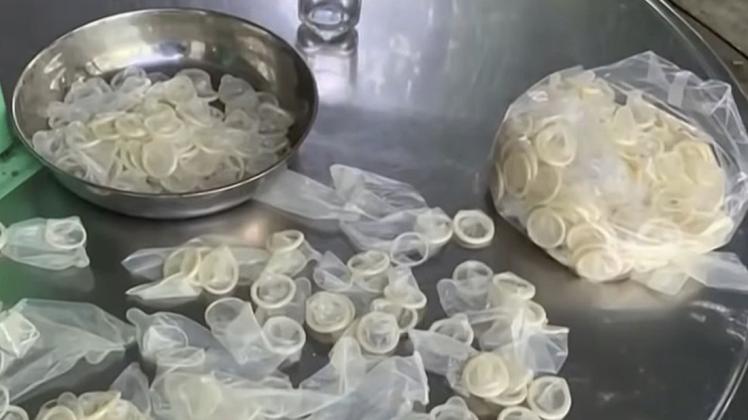 Bereits benutzte Kondome liegen auf einem Tisch, um für den Weiterverkauf verpackt zu werden.