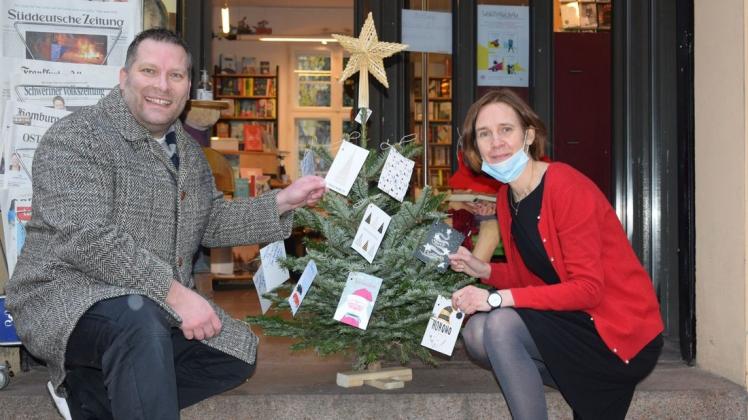Ein paar Postkarten mit Bücherwünschen hängen schon am Baum. Dr. Daniel Trepsdorf und Ladenbetreiberin Jane Kanieser hängen aber noch weitere dazu.