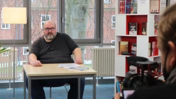 Dichter Jörg Ulrich Helgert ("JUH") trägt sein Gedicht für die Kulturclips in der Parchimer Stadtbibliothek vor.