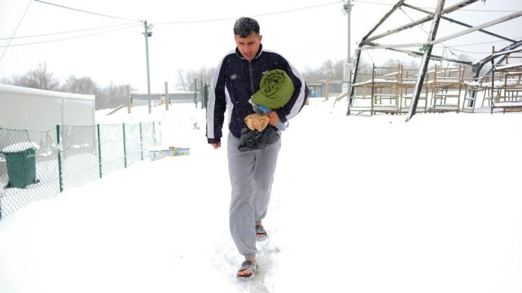 Ein Migrant aus dem Aufnahmelager Lipa bei Bihac geht am Samstag mit einer Decke unterm Arm und offenen Schuhen durch den Schnee.