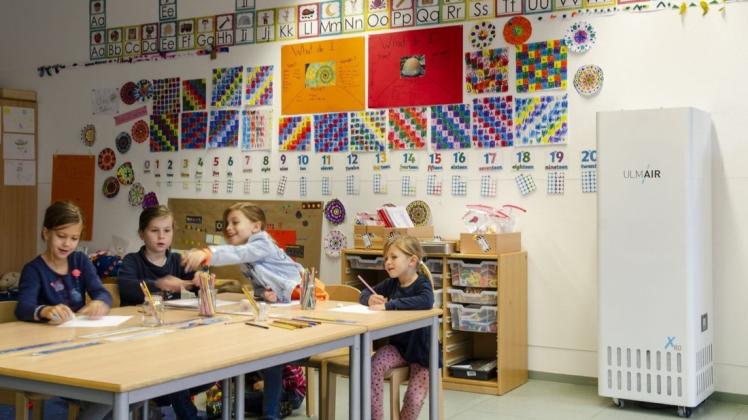 Lernen und automatisch lüften: Das Symbolbild zeigt Kinder in einer Schulklasse, deren Luft zum Schutz vor Corona von einem mobilen Filtersystem gereinigt wird. (Herstellerfoto)