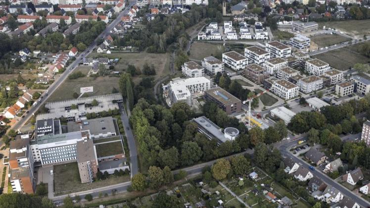 Die geplante Erschließungsstraße zieht sich in Nord-Süd-Richtung durch den Grünstreifen. Rechts der Wohn- und Wissenschaftspark, links die Paracelsus-Klinik. Das Luftbild entstand 2019.