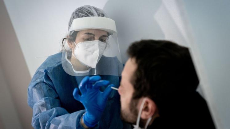 Medizinisch geschultes Personal nimmt einen Mund- und Nasenabstrich für einen Corona-Schnelltest.