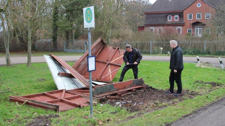 Bürgermeister Marko Schiefelbein und Dachdeckermeister Sven Möller begutachten die Reste des Wartehäuschens, um die Höhe des Schadens einschätzen zu können.