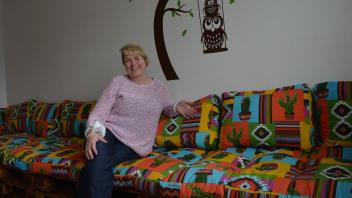 Monika Fricke sitzt auf der neuen Couch, die aus Euro-Paletten entstand. Sie freut sich über die farbenfrohe Sitzgelegenheit.