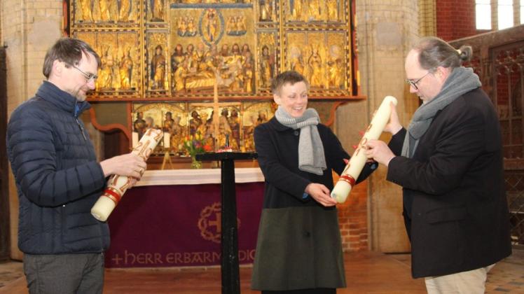 Pfarrer Tobias Sellenschlo (r.) übergibt Pastorin Johanna Levetzow das Osterlicht. Pastor Michael Fiedler räumt dafür die alte Kerze beiseite.