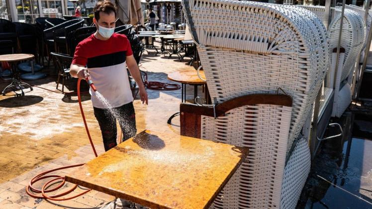 Ein Mitarbeiter des Cafes "Wichtig" in Timmendorfer Strand bereitet die Sitzplätze auf der Außenterrasse vor.