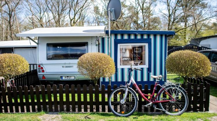 Ein Fahrrad steht an einem Gartenzaun vor einem Wohnwagen auf dem Campingplatz der Familie Wilken an der Thülsfelder Talsperre.