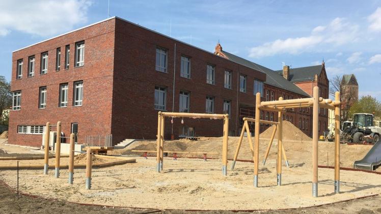 Blick auf den neuen Anbau der Wismarer Fritz-Reuter-Schule. Auf dem Schulhof werden neue Spielgeräte aufgebaut.