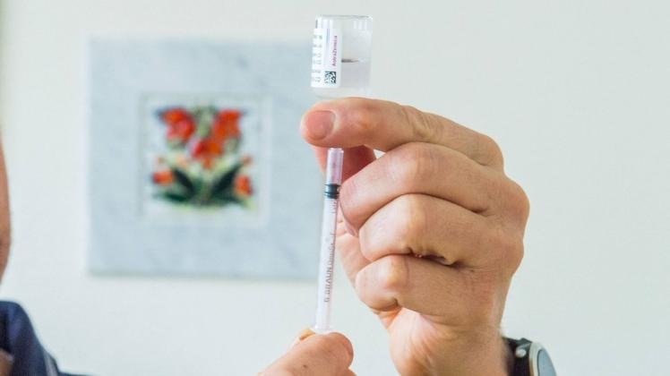 Eine Hausarzt zieht mit einer Spritze eine Impfdosis des Impfstoffes Astrazeneca aus einer Ampulle.