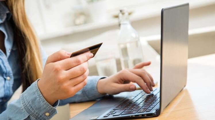 Eine Frau tippt beim Online-Shopping die Nummer ihrer Kreditkarte auf einem Laptop. Banken und Sparkassen führen nun nach und nach ihre Online-Bezahlverfahren Paydirekt, Giropay und Kwitt unter der Marke Giropay zusammen.
