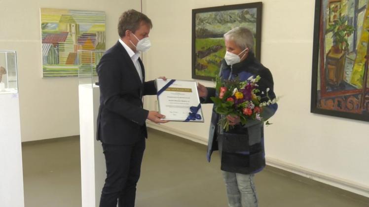 In den Ausstellungsräumen des Kunst-Wasser-Werks nimmt die Vorsitzende des Trägervereins, Gabriele Szymanski, die Auszeichnung von OB Rico Badenschier entgegen.