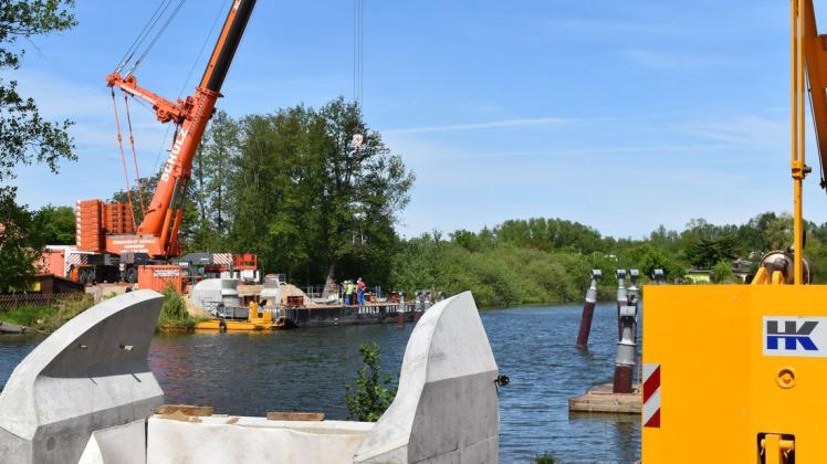 Der rote Mega-Kran der Firma Krandienst Schulz soll ab Donnerstag die Brückensegmente auf die Betonwiderlager und die drei Pfeiler im See heben.