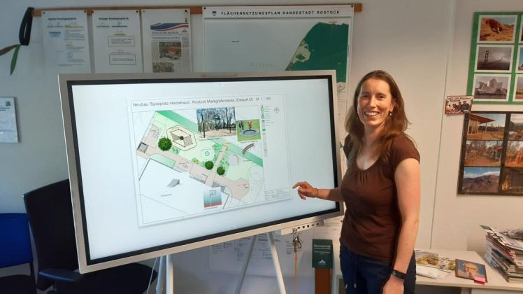 Planerin Doreen Hendler zeigt am Sidebord, wie der Spielplatz Heidespaß vor dem Heidehaus in Markgrafenheide aussehen soll.