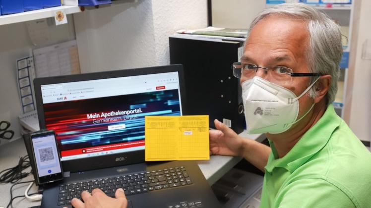 Thomas Schaefer, Inhaber der Andreas-Apotheke in Delmenhorst, zeigt den digitalen Impfpass auf dem Smartphone neben der weiterhin gültigen Version auf gelbem Papier.