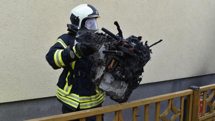 Der Brandherd: Einer der Brandschützer bringt die völlig verkohlte Werkzeugkiste aus dem Keller.