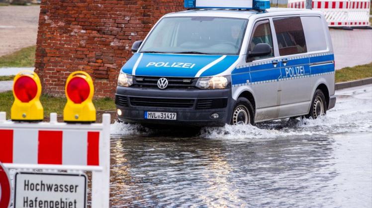 Ein Polizeiauto fährt über eine teilweise überflutete Straßenkreuzung am Hafen von Wismar. /Archiv