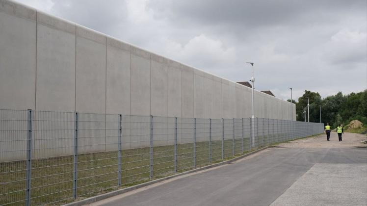 Mitarbeiter eines Sicherheitsdienstes gehen an der Außenmauer der Abschiebungshafteinrichtung Glücksstadt vorbei.