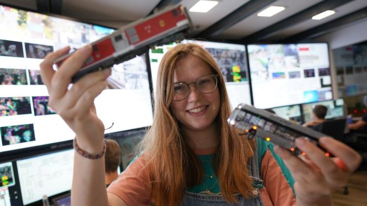 Ariana Jäger steht am Leitstand im Miniatur Wunderland und hält zwei Eisenbahnmodelle in der Hand. Seit eineinhalb Jahren arbeitet die ausgebildete Schilder- und Lichtreklame-Herstellerin im Miniatur Wunderland.