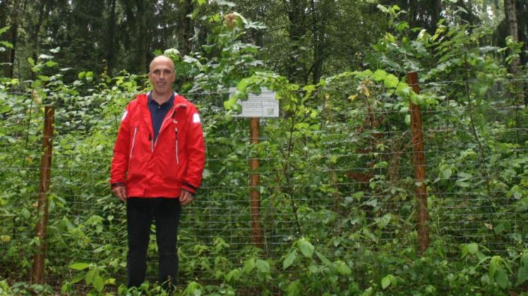 Pascal Girardot präsentiert zufrieden das Wachstum des 2019 gepflanzten Waldstückes am Bönningstedter Friedhof. Das Schild neben ihm verweist auf die Pflanzung durch Citizens Forests und soll daran erinnern, dass dieser Wald durch bürgerschaftliches Engagement entstanden ist und deswegen einen besonderen Schutz genießt.