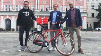 Mit einer roten Schleife versehen überreichte Karsten Pannwitt (M.), Vorstandsmitglied der Ospa-Stiftung, Tim Birkholz (r.), Geschäftsführer der AGFK MV, und Oberbürgermeister Claus Ruhe Madsen (parteilos) den mobilen Fahrradzähler im Wert von 3570 Euro.
