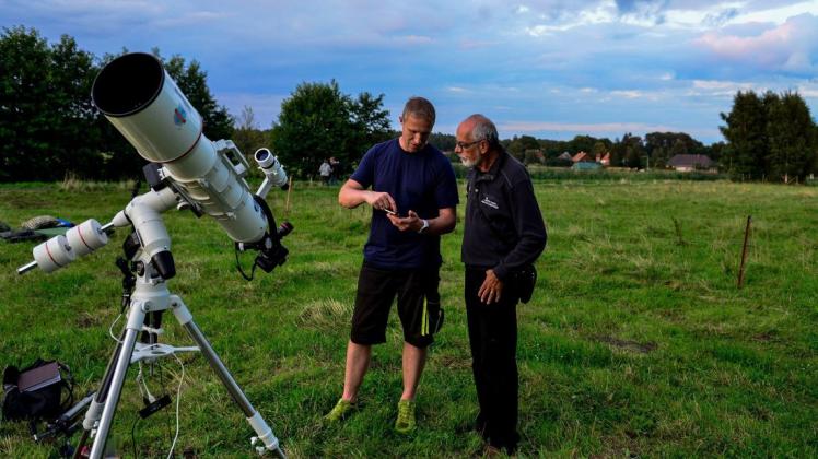Hobbyastronom Guido Strauß (Mitte) erklärt einem Besucher der Sternschnuppennacht die Steuerung seines Teleskops.