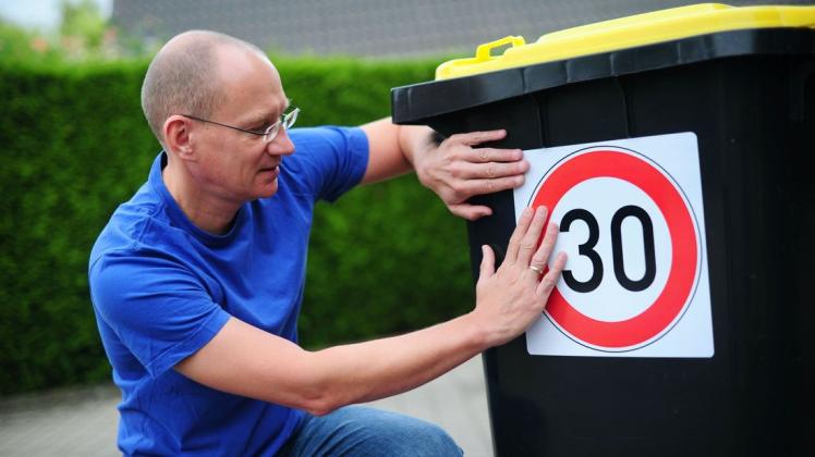 Der FDP-Politiker Alexander Sprick beklebt seine Mülltonne.