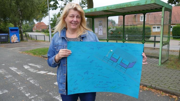 Bürgermeisterin Andrea Bennühr zeigt das Plakat, das die Kinder und Jugendlichen gemalt haben, die sich für Lüblow eine neue Buswarte wünschen.