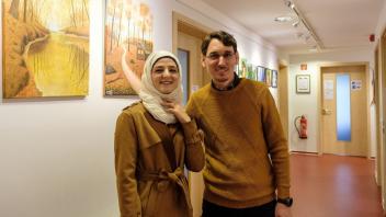 Die Künstlerin Noura Husainato und ihr Mann Mohamed Noor Kayali stehen neben den vom Herbst inspirierten Werken.