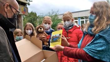 Die Betreuerin der Gute-Taten-Scouts Tanja Hinghaus (rechts) zeigt Siegfried Held vom Kinderhospiz Löwenherz das Album von der Müllsammelaktion.