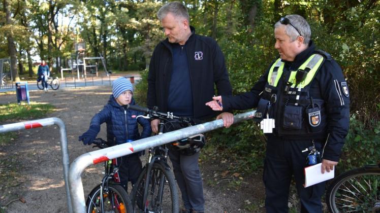 Kontaktbeamter Karsten Meyer erklärt dem sechsjährigen Ansgar, Sohn von Mathias Stagat (Mitte), das richtige Verhalten, wenn man den Spielplatz verlässt.
