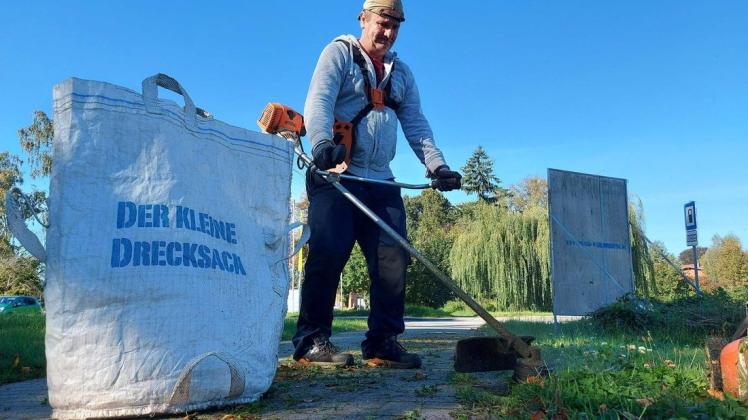 Mit dem Trimmer und dem „kleinen Drecksack“ unterwegs: Thoralf Peters sorgt für Ordnung auf den Grünflächen am Zwei-Seen-Center in Warin.
