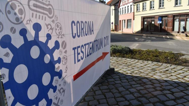 Mit einem großen Plakat wird in der Einkaufsstraße von Bützow auf das Corona-Testzentrum hingewiesen.