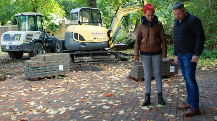 Melanie Weber und Christian Gadow vom Karstädter Bauamt schauen sich die neue Pflasterung an der Blockhütte in Stavenow an.