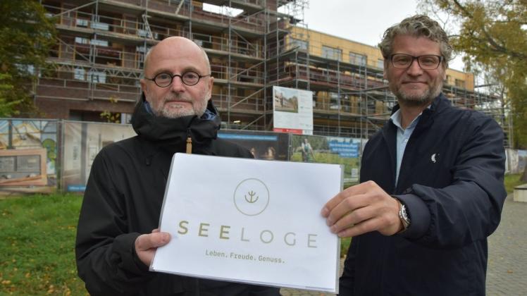 Investor Reinhard-Ehmke Sohns und Bauleiter Stephan Barnstedt lüften das Geheimnis und zeigen den Namen des neuen Hotels an der Stadtbucht.