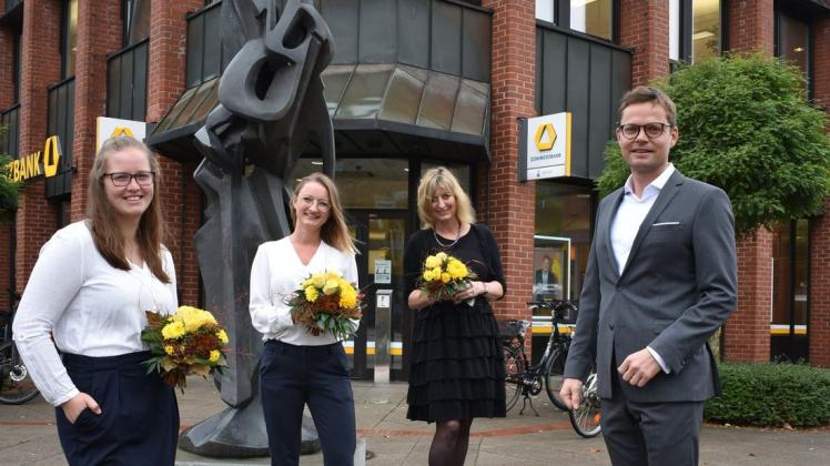 Jan Buchholz (Leiter Marktbereich von links) mit Tina Brütt (Kreditmanager), Daniela Sierks (Privatkundenbereich) und Susanne Kunze (Unternehmerkundenberatung) vor der Bronzeplastik der Künstlerin Ulla Scholl. Die Skulptur wurde 2019 aufgestellt.