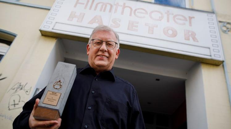 Anfang und Ende eines Berufslebens fürs Kino: Hermann Thieken zeigt vor seinem ersten Kino, dem Filmtheater Hasetor, den Ehrenpreis der AG Kino-Gilde Deutscher Filmkunsttheater, den er zum Abschied erhalten hat.
