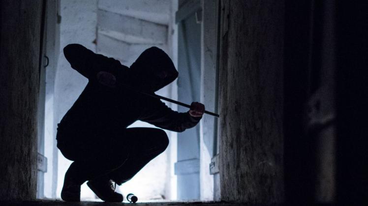 Ein „Einbrecher“ hebelt mit einem Brecheisen eine Tür im Keller eines Wohnhauses auf (gestellte Szene, Symbolbild).