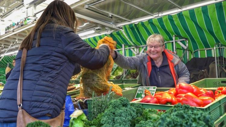 Auf dem Lingener Wochenmarkt überreicht eine Händlerin ihrer Kundin das erworbene Gemüse.
