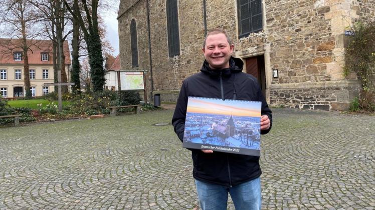 Christian Senft zeigt seinen neuen Bramscher Fotokalender vor der Kirche St. Martin. Das Gotteshaus in der Innenstadt ist auch auf dem Deckblatt zu sehen.