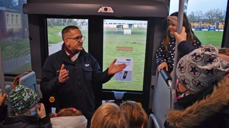 Busfahrer Jan Stanek erklärt den Kindern, warum sie nicht im Türbereich stehen sollen und auf die gelbe Linie am Boden achten sollen.